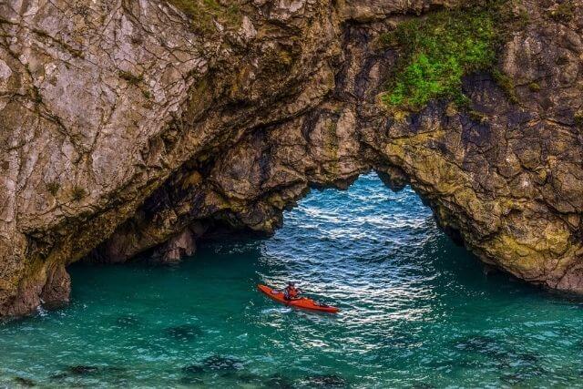 Man kayaking by rock formations near Lulworth Cove