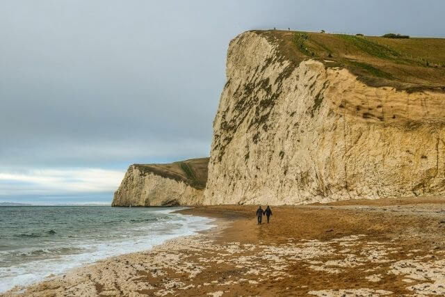 Two people walking hand in hand along the Jurassic Coast