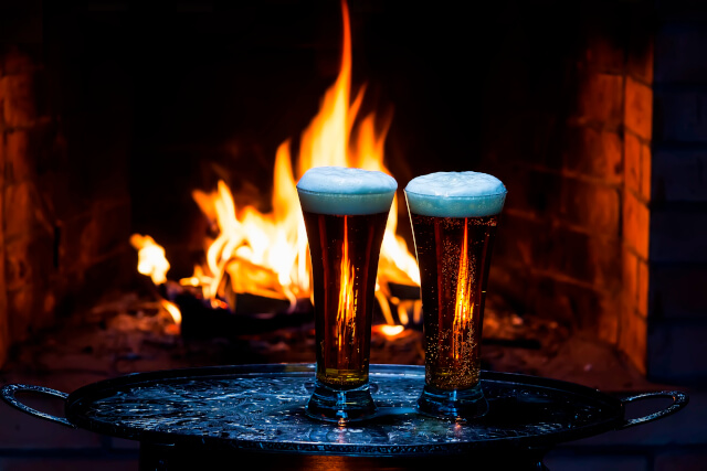 Two beers with log fire in background