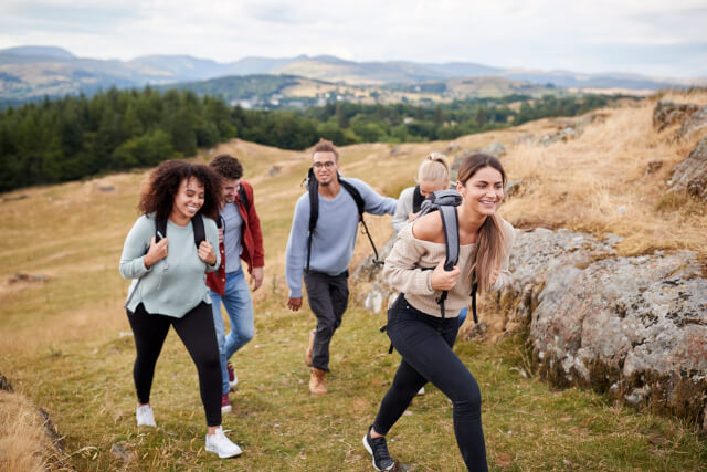 Group of five friends walking up a hill