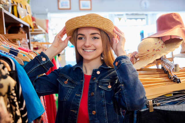 Woman trying on hat in Weymouth charity shop